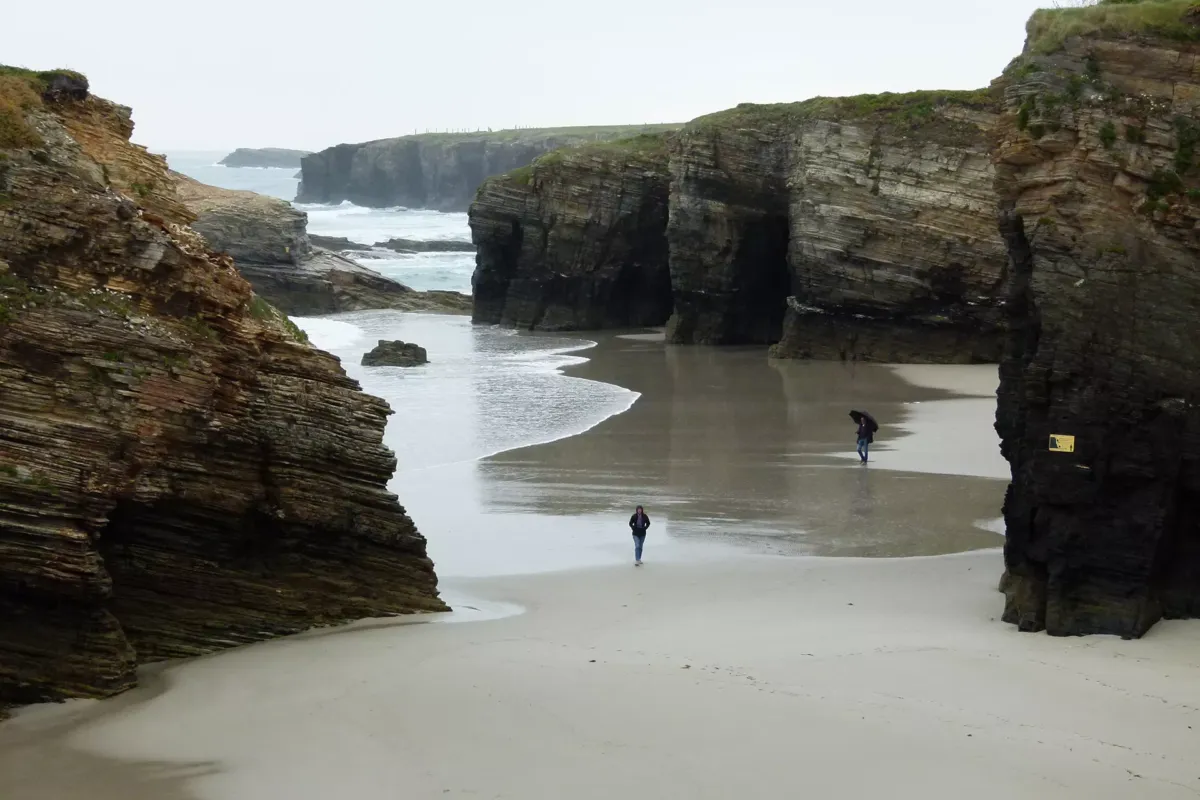 Rocas y gente paseando en la playa