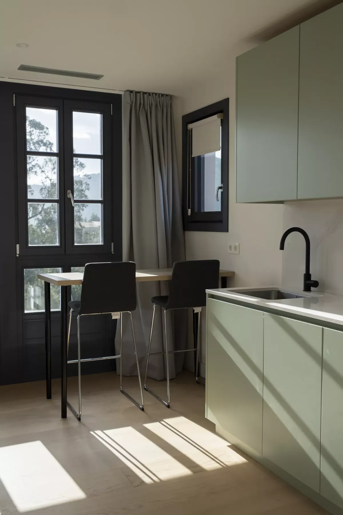 Mesa con banquetas, grifería de cocina y ventana al exterior