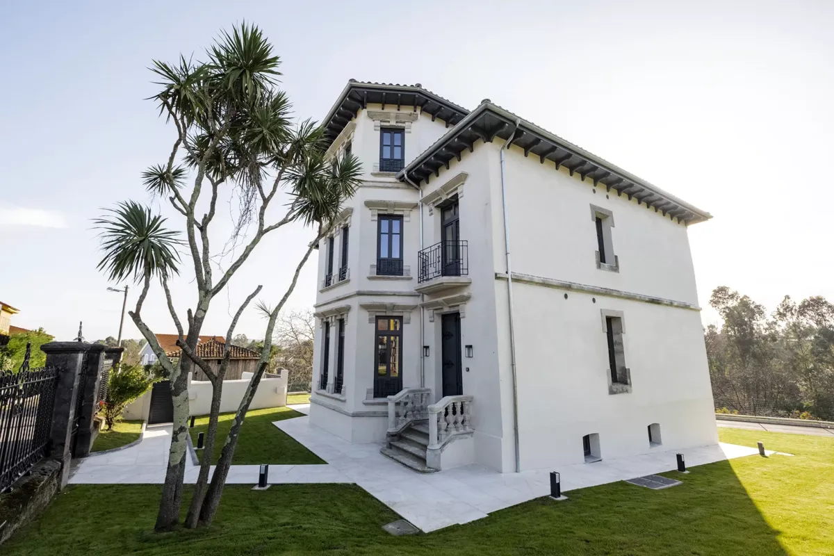 Casa de hospedaje con árboles en el frente y jardín