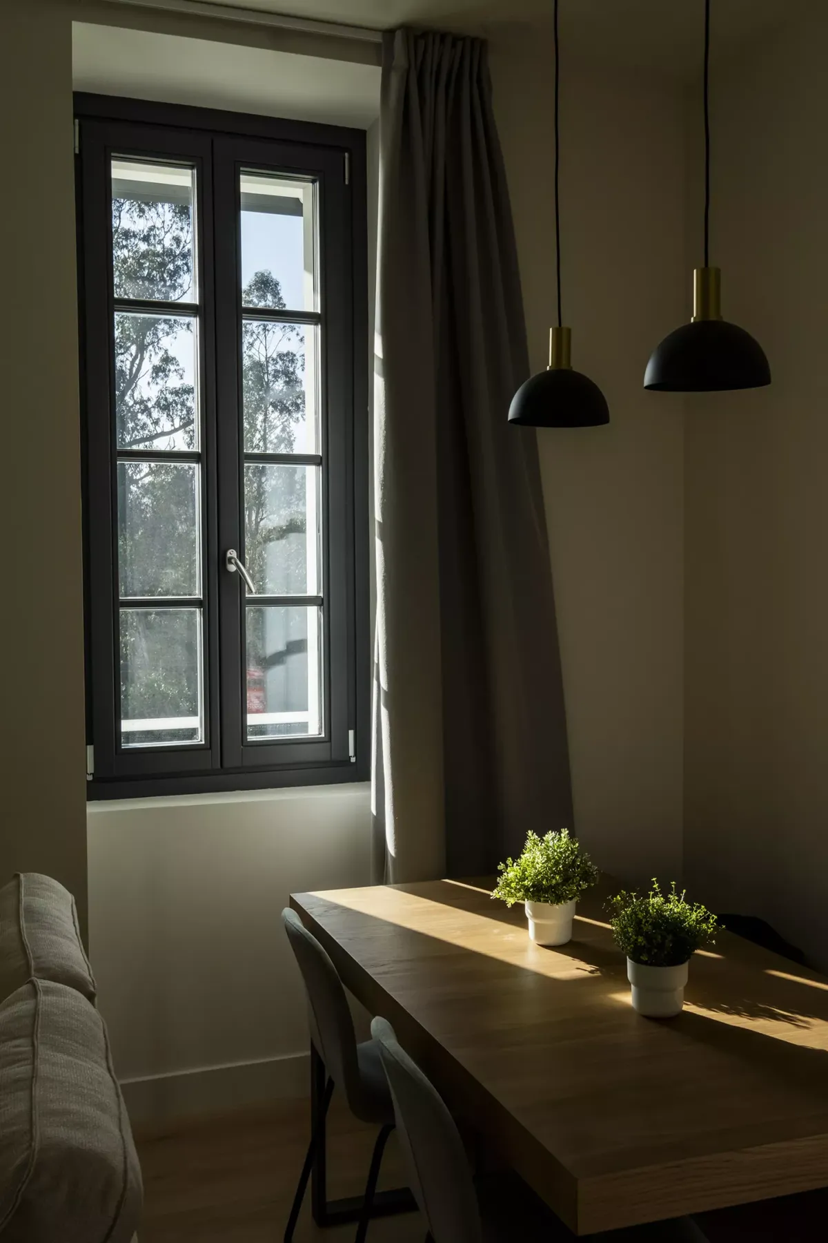 Mesa con dos plantas, lámpara, ventana y cortinas