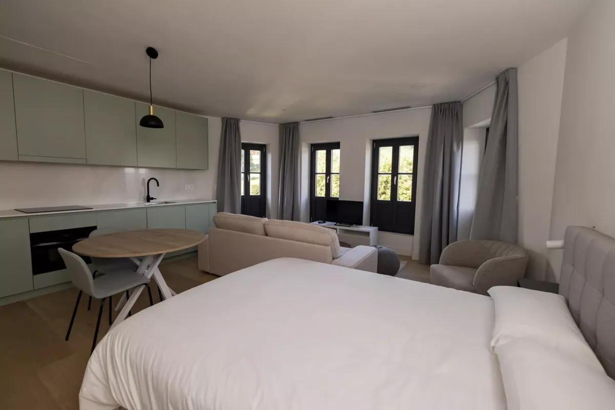 Cama de matrimonio, mesa, juego de sofá, TV y ventanas